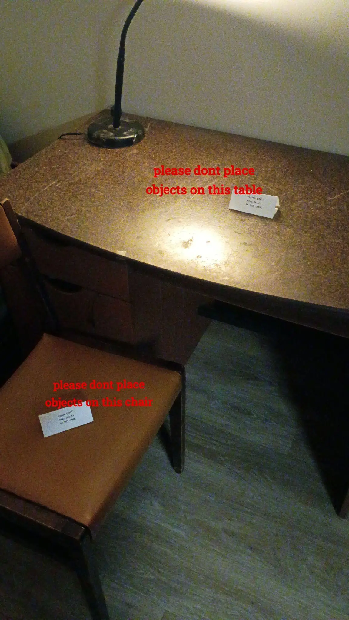 a nearly empty table with a sign that says "please dont place objects on this table". a chair that says the same